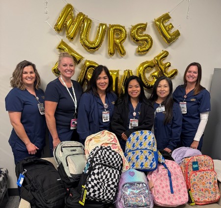 Nurse triage team smiling while showcasing the backpacks donated